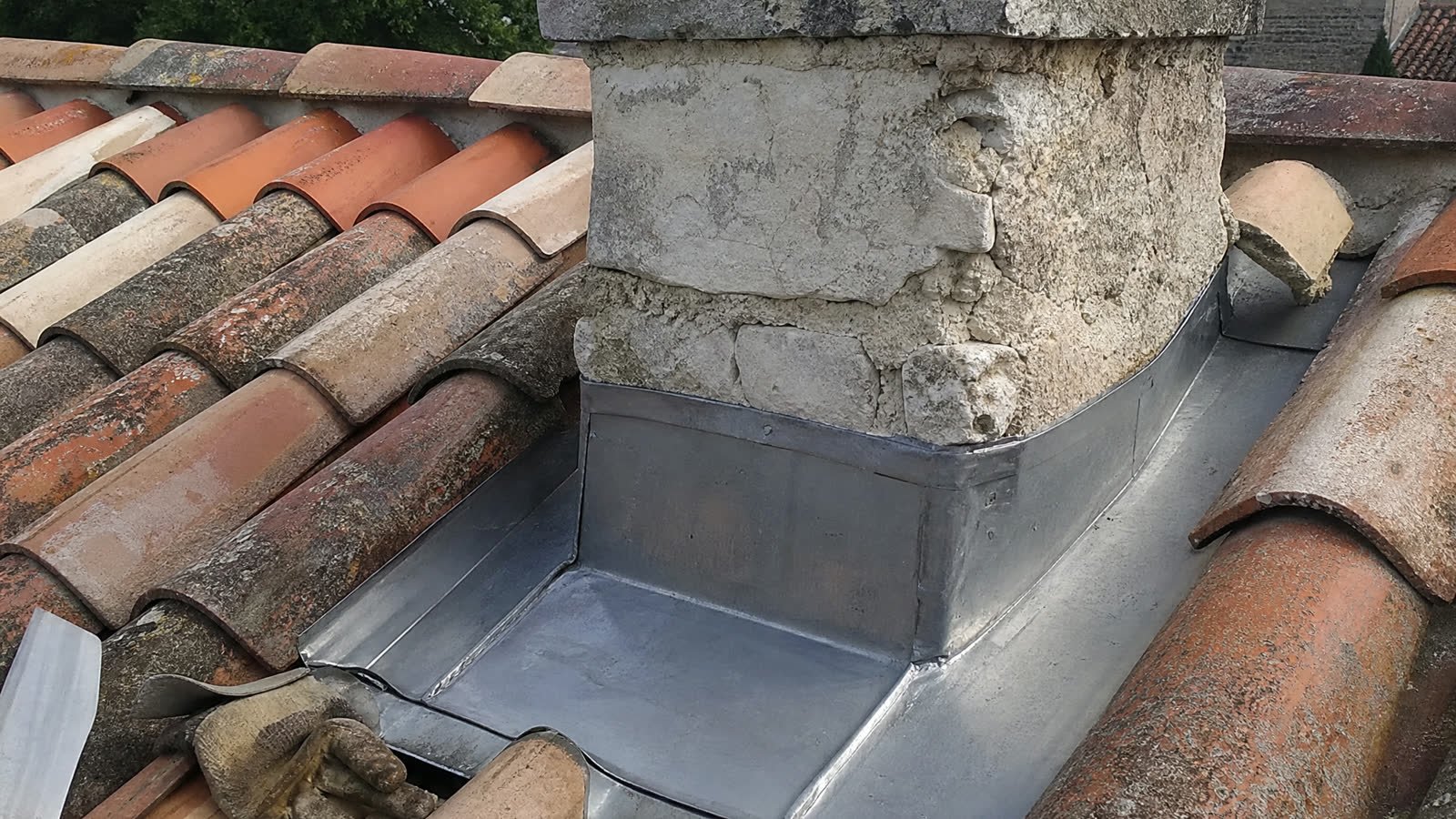 Solin en zinc refait autour d'une souche de cheminée sur une toiture en tuiles canal