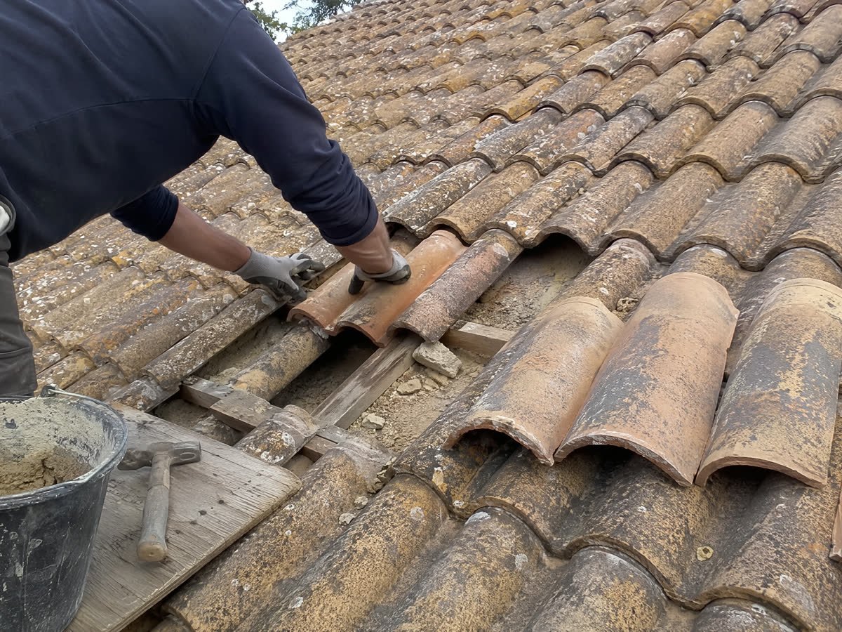 Couvreur remplaçant des tuiles cassées sur un toit nîmois